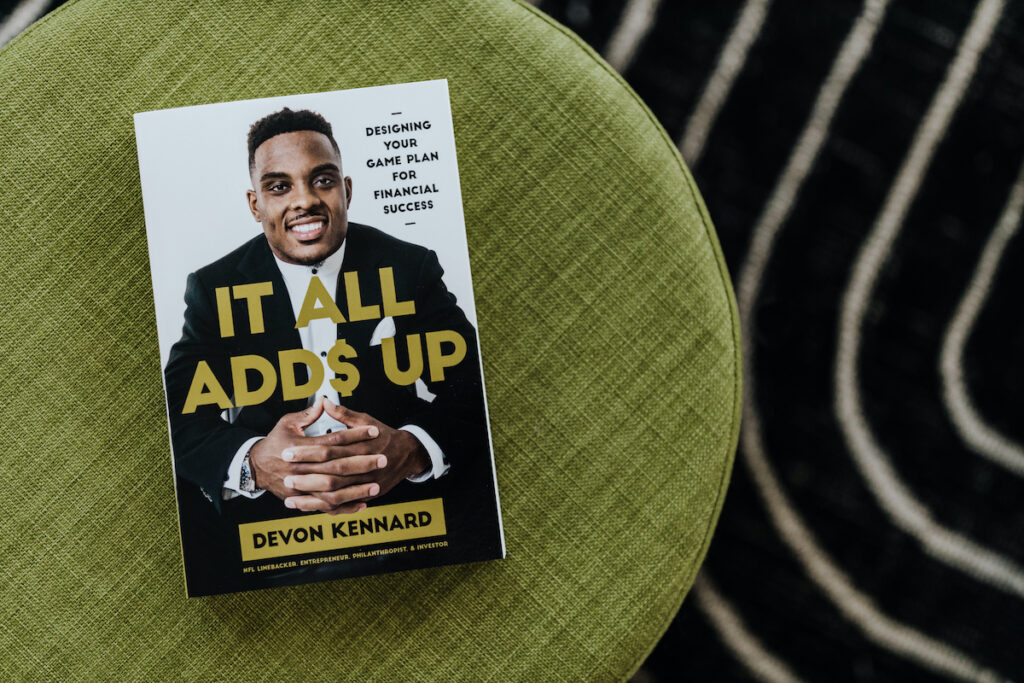 Paperback of It All Adds Up laying on a stool