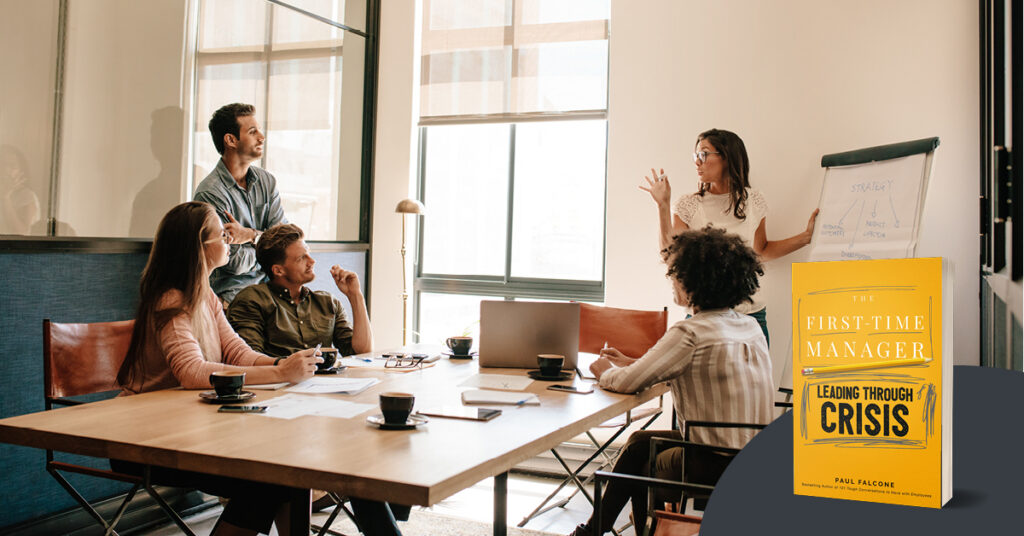 Coworkers discussing around a table, with one woman pointing at a presentation aid